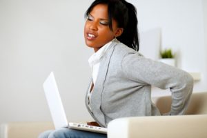 14547746 - portrait of a young woman with back pain sits down on sofa at home